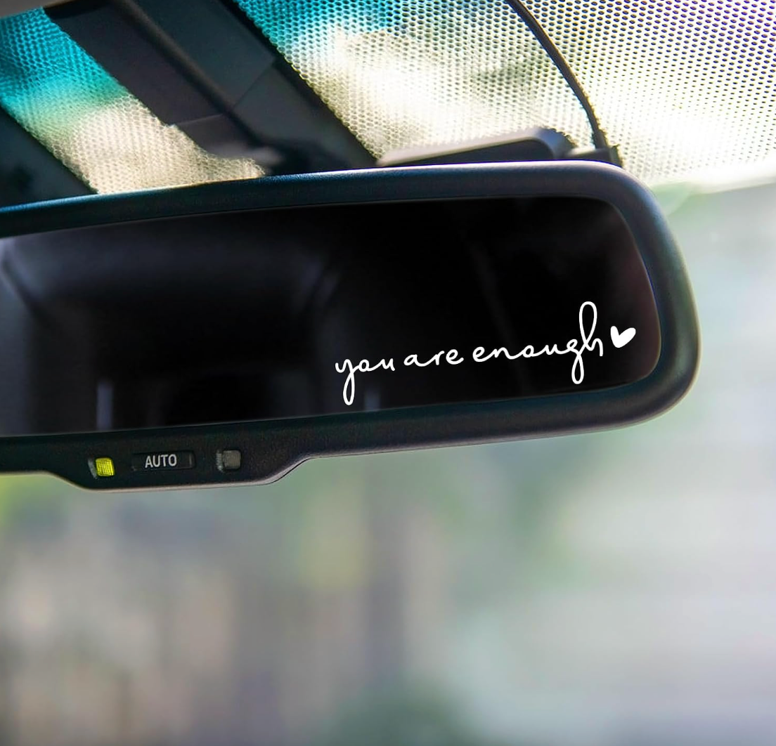 a small window call on the corner of a car's rearview mirror that says you are enough in white lettering